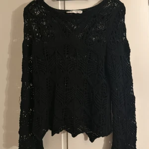 Svart virkad långärmad tröja från Zara - Svart långärmad tröja från Zara med snyggt virkat mönster och genombruten design. Tröjan har rund hals och ett unikt geometriskt mönster som ger en cool och trendig vibe. Perfekt att styla med jeans eller kjol. 