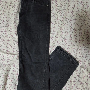 Svarta slim jeans från 157 - Svarta jeans från 157 med slim passform och klassisk femficksdesign. Jeansen har dragkedja i gylfen och är tillverkade i ett mjukt jeansmaterial som sitter snyggt på benen. Perfekta för dig som gillar en smal siluett och stilren look.