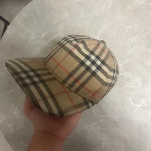 Äkta Burberry Keps - Säljer denna äkta burberry kepsen, den har några slitage men syns knappast. Hör av vid minsta lilla. Ny pris: 4000