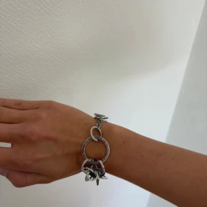 Silverfärgat armband från Edblad - Coolt armband från Edblad med stora och små ringar i silverfärgad metall. En av ringarna har Edblad-loggan runt om. Armbandet har en chunky design och stängs med en stavlås. 
