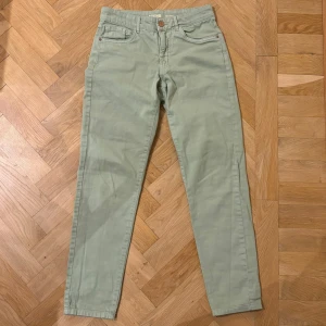 Lågmidjade ljusgröna mom-jeans, 99% bomull  - Aldrig använda, lågmidjade mom-jeans i pastellfärgen ljusgrön. Byxorna har normal passform och stängs med knapp och dragkedja. Köpta för flera år sedan på Lindex och bara legat i garderoben. 