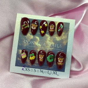 RedXmas (XXS);Short Almond;Curved - *OBS! Mindre i storlek *Handgjorda press-on naglar i vinröd färg med söta 3D-motiv av renar, stjärnor, julkrans, paket och polkagrisar. Korta Mandelformade, kurvade (mindre i storlek) och glansiga, perfekta för dig som vill ha en unik och festlig look. Material: akryl. Storlek XXS: 14 mm, 11 mm, 11,5 mm, 9 mm, 8 mm 