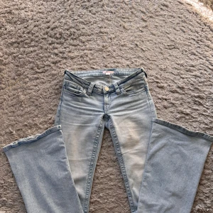 Bootcut ljusblå jeans med broderi - Snygga ljusblå bootcut jeans med klassisk femficksdesign och broderade detaljer på bakfickorna. Jeansen har låg midja och är tillverkade i mjukt denim-material som ger en skön känsla. Perfekt för dig som gillar retrovibbar och vill sticka ut med coola detaljer. Strl S😊