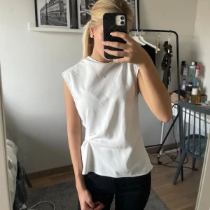 Vit ärmlös linnetopp XS - Säljer en stilren vit linnetopp i storlek XS. Toppen har en rak, något lös passform och är ärmlös med breda axlar. Materialet är slätt och lätt, perfekt för en clean look. Enkel att matcha med både jeans och kjol.