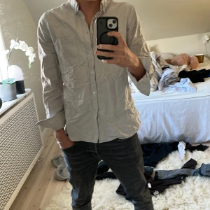 Ljusgrå skjorta från Filippa K - Snygg ljusgrå skjorta från Filippa K i klassisk modell med krage och knappar framtill.  Storlek M men passar S!