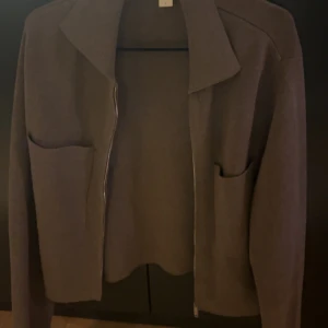 Brun cardigan jacka från Åhléns Woman - Mysig brun cardigan jacka från Åhléns Woman i stickat material. Jackan har två stora fickor framtill, dragkedja och en klassisk krage. Perfekt för lager-på-lager och chill vibes.