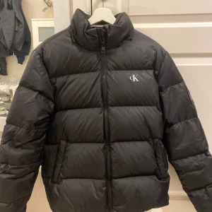 Svart pufferjacka från Calvin Klein - Svart pufferjacka från Calvin Klein. Köptes ny för 3000kr på Zalando. Använd knappt 10 gånger. Köparen står för frakt!