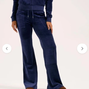 Mörkblå juicy couture byxor - Mörkblå juicy byxor i mjukt och glansigt material med bred resår i midjan och snörning framtill. Byxorna har raka ben, stora fickor fram och bak samt en relaxed passform. Perfekta för chill dagar och snygga att styla med en hoodie eller crop top. Byxorna är knappt använda, köpta 2023 på Jackie sedan dess har de endast använts en gång. Som nya, inga defekter. Tveka inte vid frågor💞