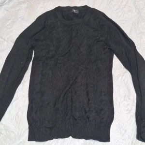 Svart stickad tröja från Oodji Lab - En svart, klassisk stickad tröja från Oodji Lab. Tröjan har rund halsringning, långa ärmar och ribbade muddar vid ärmslut och nederkant. Perfekt för lager-på-lager och enkel att matcha med olika outfits.