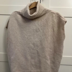 Beige stickad väst med polokrage från SHEIN - Mysig beige stickad väst från SHEIN med bred ribbad polokrage och ärmlösa öppningar. Perfekt till hösten 