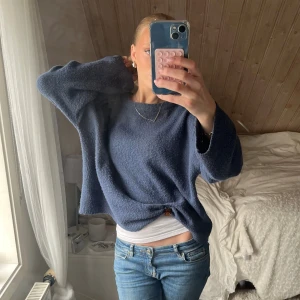 Blå oversized stickad tröja - Mysig blå stickad tröja med oversized passform och långa ärmar. Tröjan har en enkel design utan mönster och är perfekt för lager-på-lager. Materialet känns fluffigt och ger en avslappnad vibe. I m men sitter som s/xs