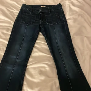 Mörka jeans med Lågmidjade - Snygga mörkblå jeans med markerade sömmar längs framsidan. Byxorna har två stora framfickor och klassisk midja. Perfekta för en trendig och avslappnad look.