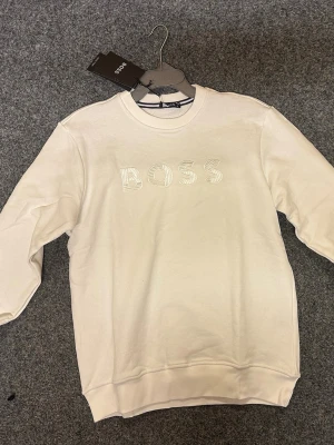 2st BOSS sweatshirt. Vit / Svart. - Snygga sweatshirts från BOSS i både vit och svart. Tröjorna har rund hals, långärmade och ett stilrent BOSS-tryck broderat på bröstet. Tillverkade i mjuk bomull för skön komfort och clean look. Perfekt för dig som gillar enkel och modern stil. 2st för 1049kr. 1st 649kr. 