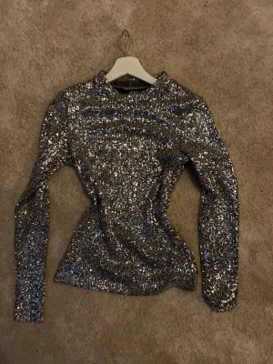 Glittrig silver topp från Monki - Säljer en glittrig långärmad topp från Monki i silver med paljetter över hela ytan. Storlek S.          Perfekt inför nyår❤️