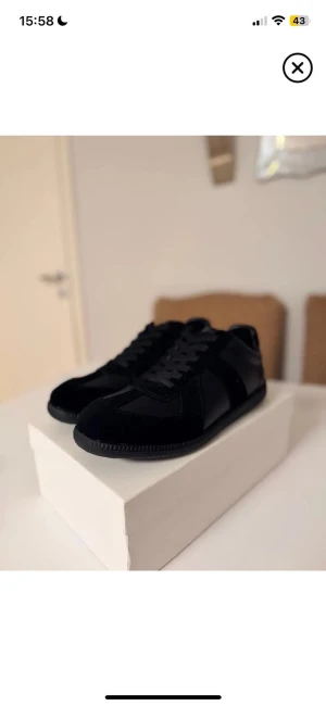 Svarta Margiela gats  -  Margiela gats  i helsvart med snygga paneler i mocka och skinn. Klassisk rund tå, platt sula och snörning framtill. Minimalistisk och stilren design som passar till allt. Kommer med originalkartong.