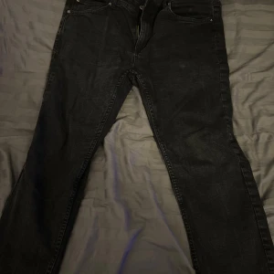 Svarta jeansbyxor från FSBN 34/30 - Svarta jeansbyxor från FSBN i klassisk femficksmodell med dragkedja och knapp framtill. Jeansen har en rak passform och är tillverkade i slitstarkt denimtyg. Perfekt för dig som gillar en enkel och stilren look.