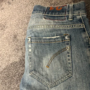Dondup jeans George  - Snygga ljusblå jeans från dondup  med klassisk femficksdesign och slitna detaljer. Jeansen har raka ben och kontrastsömmar, samt donduplogga på bakfickan. Perfekt för dig som gillar en avslappnad och stilren look. Bra skick 