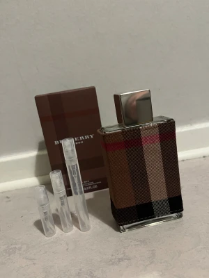 Burberry london for men  parfym med testprover - Stilren Burberry parfym i klassiskt rutigt fodral. Levereras med originalkartong och tre praktiska testprover. Volym: 3.3 FL.OZ. Perfekt för dig som vill ha en ikonisk doft i samlingen. 2ml=20kr 3ml=25kr 5ml=40kr