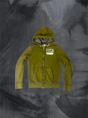 Olivgrön hoodie från Abercrombie & Fitch - Piss snygg olivgrön hoodie med dragkedja från Abercrombie & Fitch. Med en tjock huva med och en olivgrön färg är den perfekt för dig som vill ha ett bekvämt och snyggt plagg i din garderob . Kan tänka mig gå ner i pris vid snabb affär. Modellen är 188, väger 78 ish. Ha det gött!//Gidlöfs