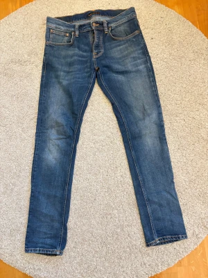 Nudie Grim Tim jeans - Hej, säljer nu dessa superfina jeans ifrån nudie i bra skick. Storleken är 31/32 och sitter slim. Jeansens ena ficka är trasig på insidan men detta lagar man gratis på valfri nudie butik. Skriv gärna om ni har frågor eller lägg gärna prisförslag då priset inte är hugget i sten.