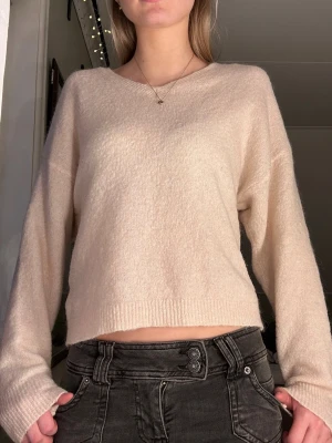 Beige stickad tröja från Ellos - Mysig beige stickad tröja från Ellos i storlek 34/36. Tröjan har en v-ringad hals och långa ärmar. Perfekt för dig som gillar en enkel och clean look med lite oversized känsla. Supermjuk och skön att bära.