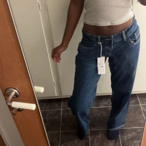 Blå baggy jeans med låg midja - Säljer ett par blå jeans med låg midja och baggy passform. Jeansen har klassiska fem fickor, kontrastsömmar och är tillverkade i jeansmaterial. Perfekta för en avslappnad och cool stil.( köpt för 399 men pris kan diskuteras)
