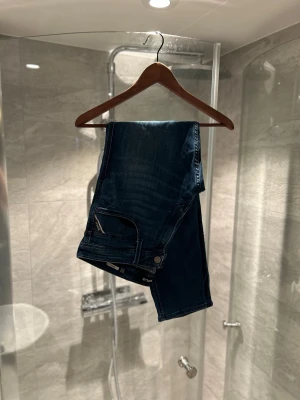 Replay Anbass jeans blå herr - Snygga Replay Anbass jeans i mörkblå tvätt med klassisk design. Modellen har normal passform och raka ben, med detaljerade sömmar och Replay-logga på fickan. Perfekt för dig som gillar stilrena och bekväma jeans.