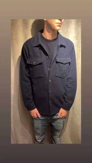 Overshirt - Snygg mörkblå overshirt med klassisk krage och stora bröstfickor med knappar. Jackan har en rak passform, knäppning framtill och är långärmad. Perfekt att slänga över en t-shirt för en chill och stilren look.