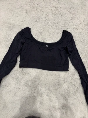 Svart croppad sport topp H&M - Säljer en svart croppad tränings topp från H&M med lång ärm och rundad halsringning. Använd ett fåtal gånger 