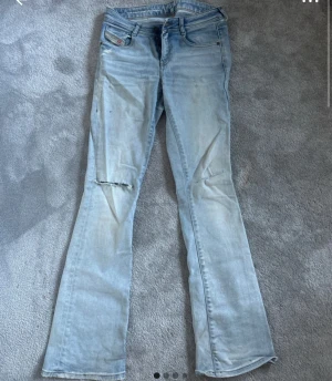 Ljusblå bootcut jeans från Diesel - Snygga ljusblå jeans från Diesel med bootcut passform och klassisk femficksdesign. Jeansen har slitningar vid knäna och coola detaljer som Diesel Industry-märken på fickorna. Tillverkade i mjukt denim-material för en avslappnad vibe. Nypris 1200 så kan tänka mig sälja för 349🥰 inga defekter. Storlek 26/32, passar mig super i längden som är 169 och bra i midjan som brukar ha s/m i kläder
