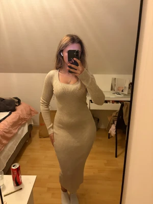 Beige ribbad långklänning - Säljer en beige ribbad långklänning med lång ärm och rundad halsringning. Klänningen är figurnära och har en snygg stretchig passform som framhäver formerna. Materialet är stickat och mjukt, perfekt för dig som gillar stilrena och enkla plagg. Aldrig använd. Är en xs men passar nog s och M också extremt stretchig. Nypris 349kr