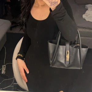 Svart långärmad klänning med rund hals - Snygg svart långärmad klänning med rundad halsringning och figurnära passform. Klänningen är enkel och stilren, perfekt för dig som gillar minimalistisk look. Materialet känns mjukt och följsamt mot kroppen. Passar dig som vill ha en klassisk svart klänning med lång ärm.