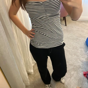 Randig bandeau tubtopp i bomull - Säljer en snygg bandeau tubtopp med svartvita ränder. Toppen är axelbandslös och har en tight passform som sitter skönt mot kroppen. Materialet är mjuk bomull och toppen har en lätt rynkning framtill för extra stil. Perfekt för dig som gillar enkel och fräsch look.