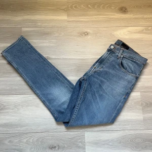 Blå tiger of Sweden jeans - Snygga blå jeans från Tiger of Sweden i modellen Pistolero, storlek 31/32. Klassisk femficksdesign med orangea sömmar och rak passform. Jeansen har en normal midja och är tillverkade i slitstarkt denimtyg som ger en snygg och tidlös look.