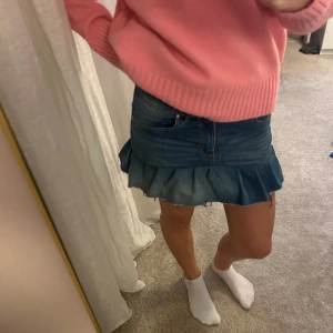 Blå jeanskjol med volangkant - Säljer en blå jeanskjol i kort modell med volangkant nertill. Perfekt för dig som gillar denim och vill ha en kjol med lite edge.