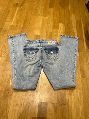Ljusblåa bootcut true religion jeans 🩵 - Super snygga ljusblåa jeans från true religion i storlek 23 med röda detaljer på bak fickorna jeansen har hål på knäna och har en bootcut model och är mid rise🤗 köpte dom förra året på Nelly och seljer på grund av att de inte kommer till användning längre 🥰
