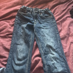 Blå bootcut jeans med klassisk look - Snygga blå jeans med bootcut passform och klassisk femficksdesign. Jeansen har kontrastsömmar och är tillverkade i slitstarkt denimtyg. Perfekta för dig som gillar en retro vibe och vill ha ett par jeans med lite vidare ben.