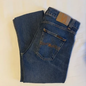 Blå skinny jeans från Nudie Jeans - Snygga blå jeans från Nudie Jeans med klassisk femficksdesign och kontrastsömmar på bakfickorna. Modellen är skinny fit med normal midja och tillverkad i mjukt denimtyg av bomull. Perfekta för dig som gillar en smal siluett och stilren look.