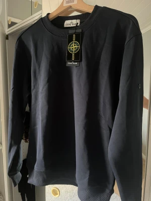 Mörkblå sweatshirt från Stone Island - Säljer helt ny stone Island tröja med stone Island märket på armen som du enkelt kan ta av och på. Storlek S hör av er vid frågor och funderingar 