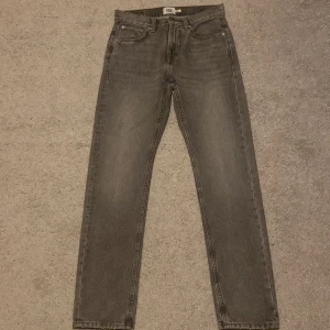 Grå jeansbyxor från 157 - Snygga grå jeansbyxor från 157 med klassisk femficksdesign och raka ben. Jeansen har en mörkgrå tvätt och är tillverkade i slitstarkt denimmaterial. Passar dig som gillar en enkel och stilren look med normal passform.