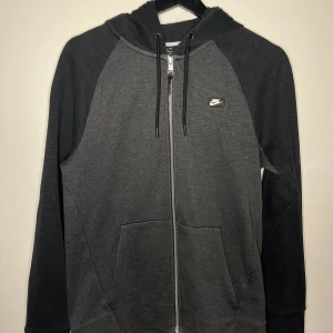 Nike hoodie med dragkedja grå och svart - Grå och svart Nike hoodie med dragkedja i mycket bra skick, pm vid intresse.