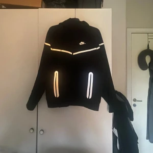 Nike Tech Fleece - Säljer en Nike Tech Fleece då den inte passar mig, en nyare modell som även är reflekterad då de vita på tröjan lyser när man tar bild med blixt. Tröjan är 10/10 skick då den aldrig är använd, skickade inte den i tid så de gick inte att returnera. De står XL på lappen men den passar nog L, kanske till och med M. Om du har frågor eller är intresserad så är det bara att höra av dig🤝