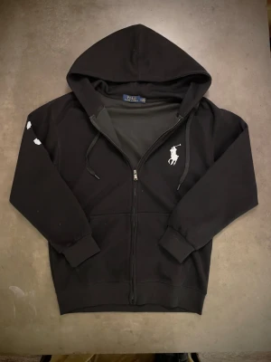 Polo RL Zip big pony - Svart zip hoodie från Polo Ralph Lauren med big pony logga. Storlek M. Riktigt snygg tröja, har knappt kommit till användning då den inte riktigt passade mig. 