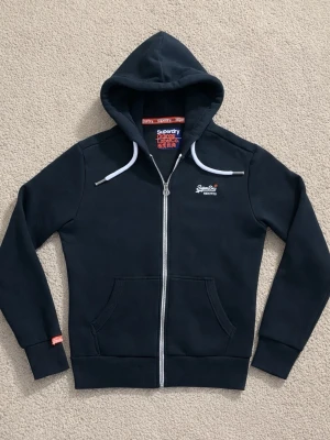 Superdry Hoodie - Svart Superdry Hoodie med Dragkedja. - Tröjan är helt ny med pris lapp. - Storlek: M - Pris: 449 kr - Först till Kvarn!