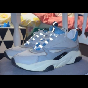 Chunky grå och blå sneakers - Säljer ett par chunky sneakers i grått och blått med vita detaljer. Skorna har en tjock vit sula med svarta partier och meshpaneler för extra ventilation. Snygg design med sportig känsla och coola detaljer på snörningen.