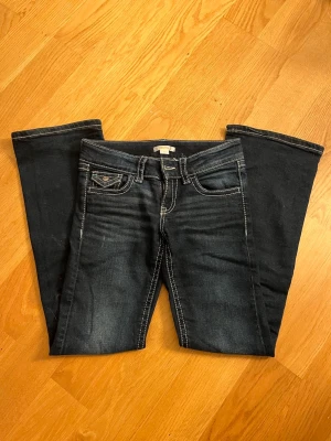 Mörkblå bootcut jeans med kontrastsömmar - Snygga mörkblå bootcut jeans med vita kontrastsömmar. Jeansen har lätt slitna detaljer framtill och utsvängda ben. Perfekta för en avslappnad och trendig look. Finns inga defekter på eller nått sånt! Passar perfekt till allt!💕💕 