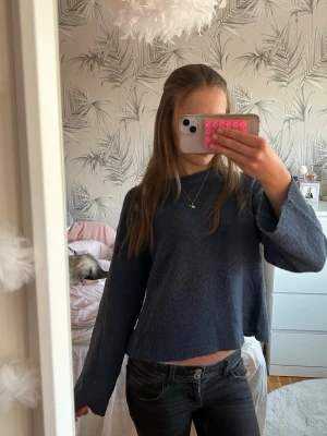 Mörkblå stickad tröja med vida ärmar - Mysig mörkblå stickad tröja med avslappnad passform och vida ärmar. Tröjan har en något kortare modell och rund halsringning. Perfekt för lager-på-lager och passar till jeans eller kjol.