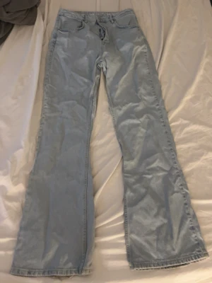 Ljusblå bootcut jeans - Säljer ett par ljusblå bootcut jeans i klassisk denim med fem fickor och normalhög midja. Jeansen har vida ben och en avslappnad passform, perfekta för en trendig och avslappnad stil. Materialet är bomullsdenim.