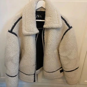 Beige teddyjacka från Zara - Naturvit teddy biker jacka från Zara. Storlek XS. Jackan har en liten fläck som syns på bild nr 2, därav priset 