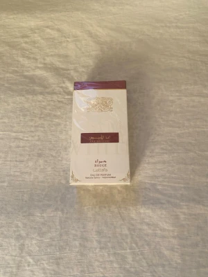 Lattafa Ana Abiyedh Rouge Parfym - Lattafa Ana Abiyedh Rouge Eau de Parfum är en elegant parfym i en vit och vinröd kartong med guldiga detaljer. Flaskan rymmer 60 ml och doften är känd för sina orientaliska och lyxiga toner. Perfekt för dig som vill sticka ut med en unik signaturdoft.Pris kan diskuteras 